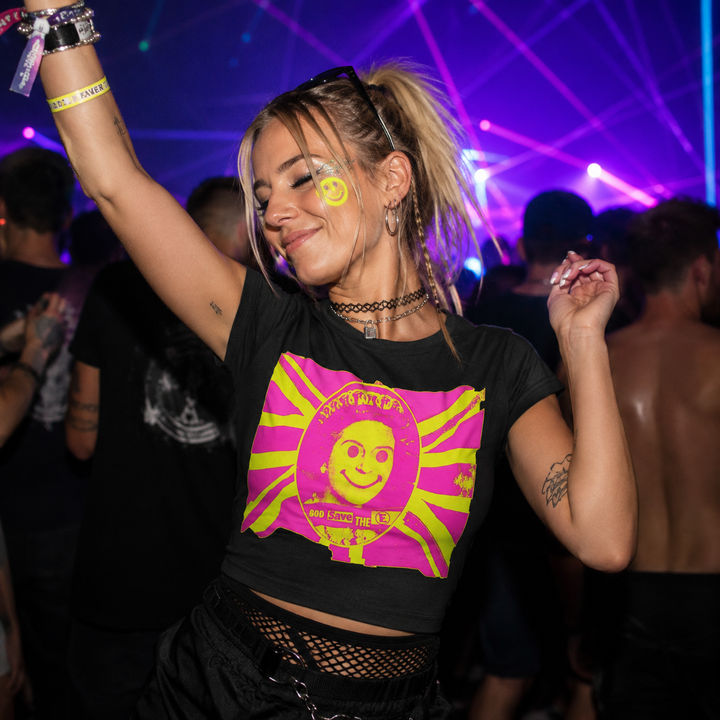 A woman dancing at a nightclub wearing a black crop top t-shirt with a bright pink and yellow graphic print of Double Good God Save the E.