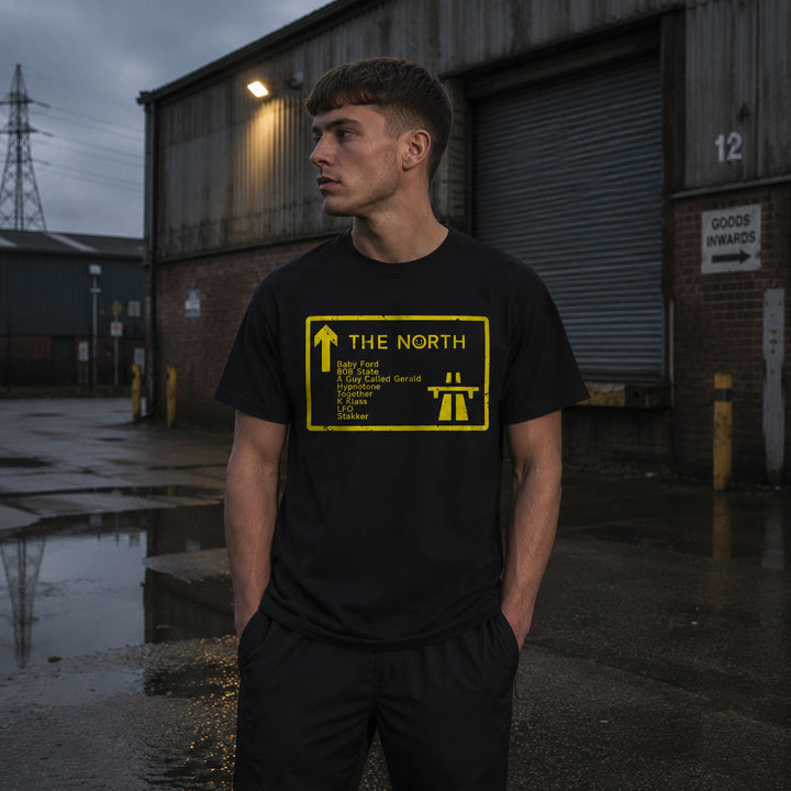 A man wearing a black t-shirt with a yellow 'The North' acid house dj and producers  graphic 