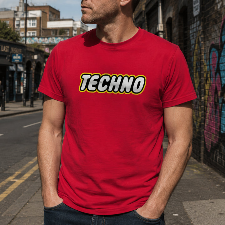 A man wearing a bright red crewneck t-shirt with a 'TECHNO' graphic printed across the chest, standing on an outdoor city street.