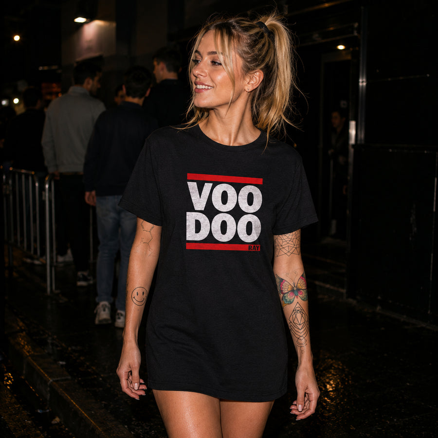 A woman wearing a black oversized graphic T-shirt with 'VOO DOO RAY' printed in white and red, walking outdoors at night.